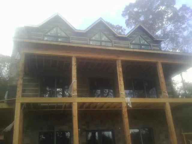 Dormers and porch framing on a large log home under construction — Roof Coating work by our crew in Laurel Hill