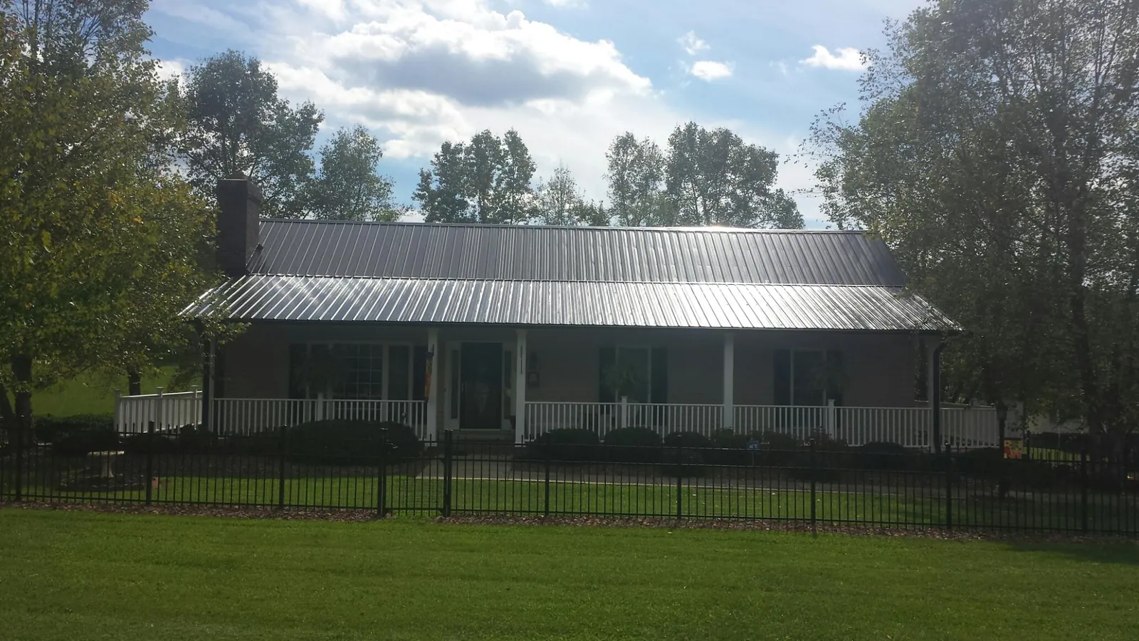 Gray metal roof on a brick ranch with a full width front porch — Gutter Guard Installation work by our crew in Laurel Hill