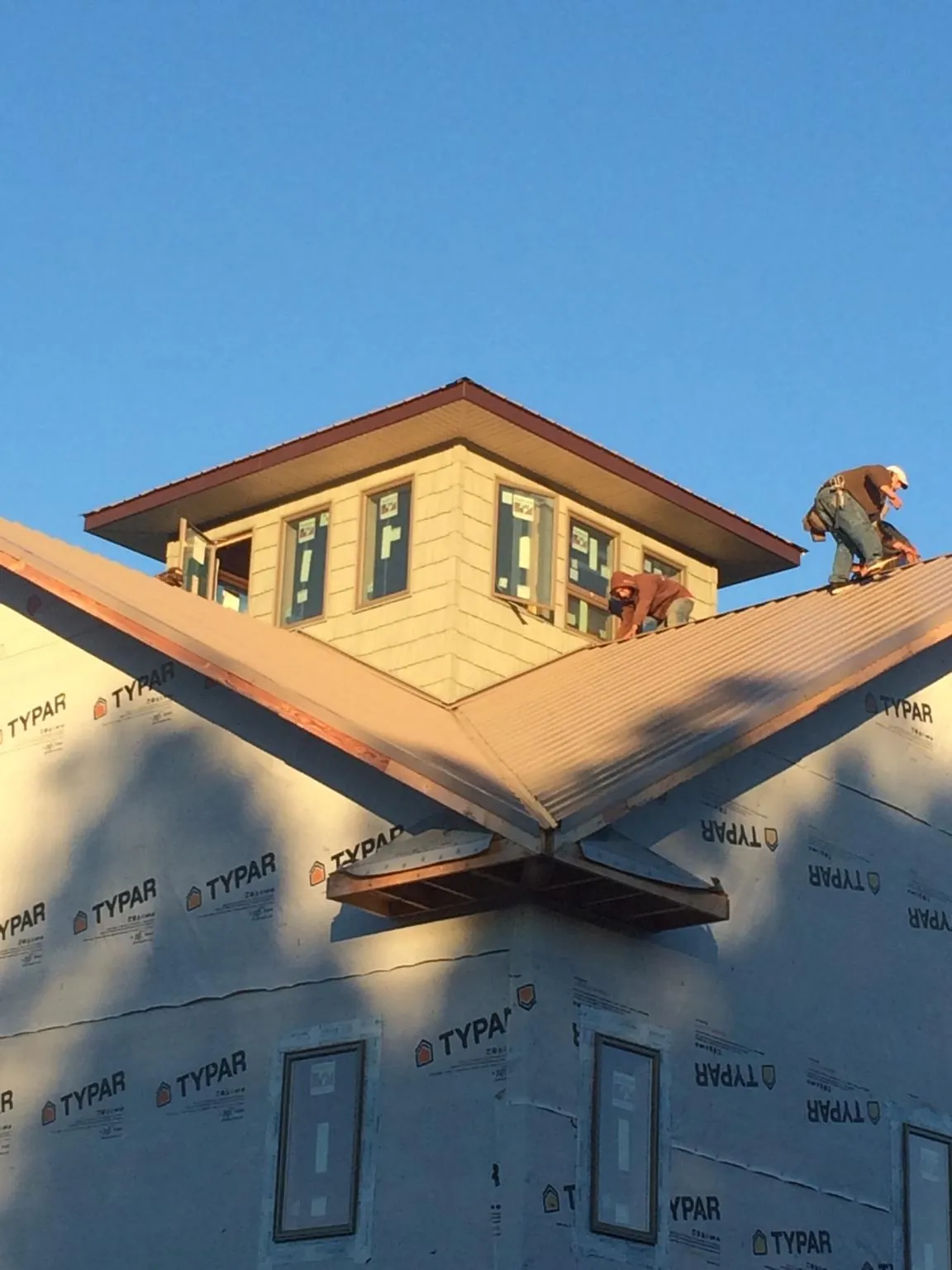 Roofers working around a rooftop cupola on a new metal roof at sunset — Roof Waterproofing in Laurel Hill by Roofing Brothers